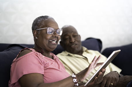 Older person sitting on a couch using a laptop